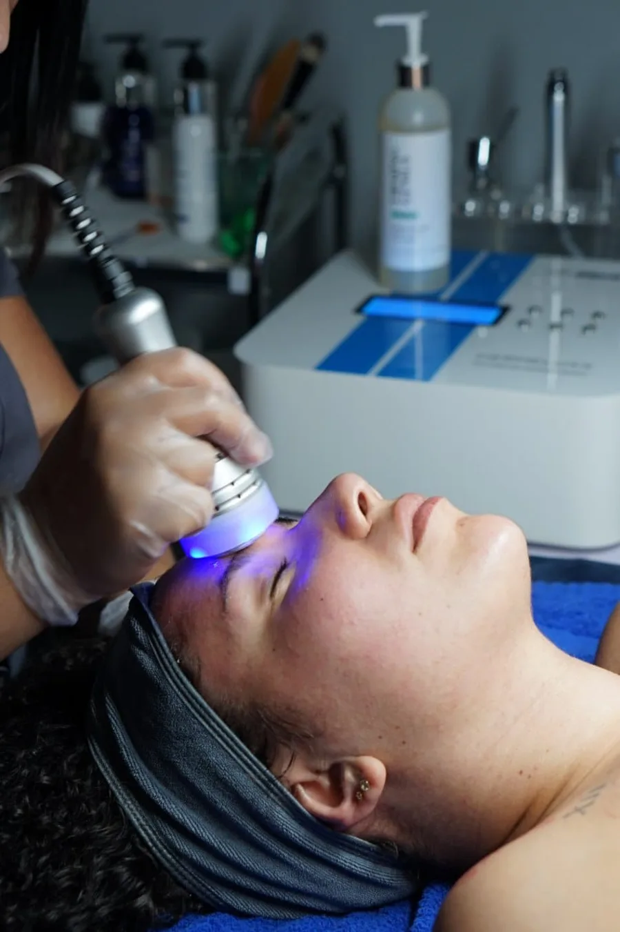 An esthetician performing a facial treatment with a professional device at Faciallash Lounge