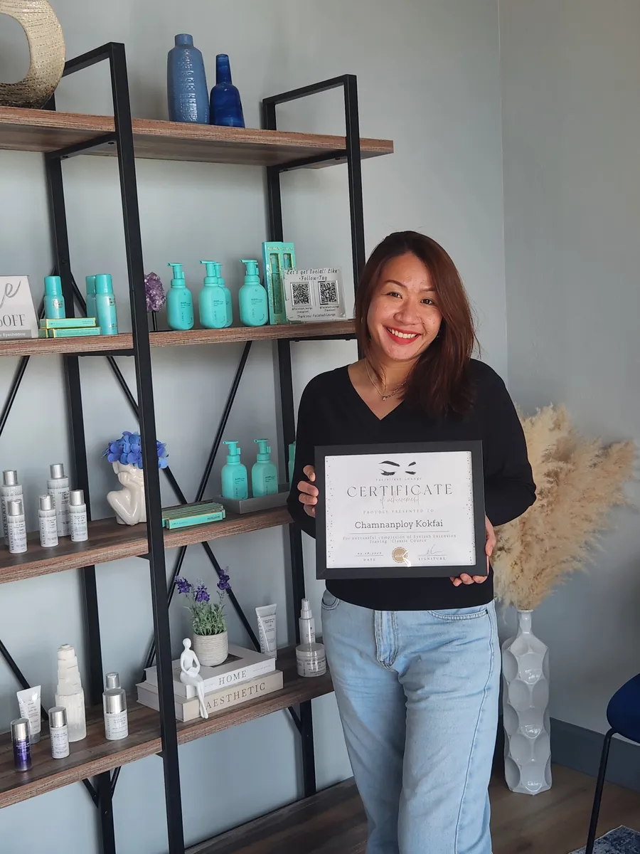 Smiling lash student holding a framed Faciallash Lounge certificate for the Classic lash course